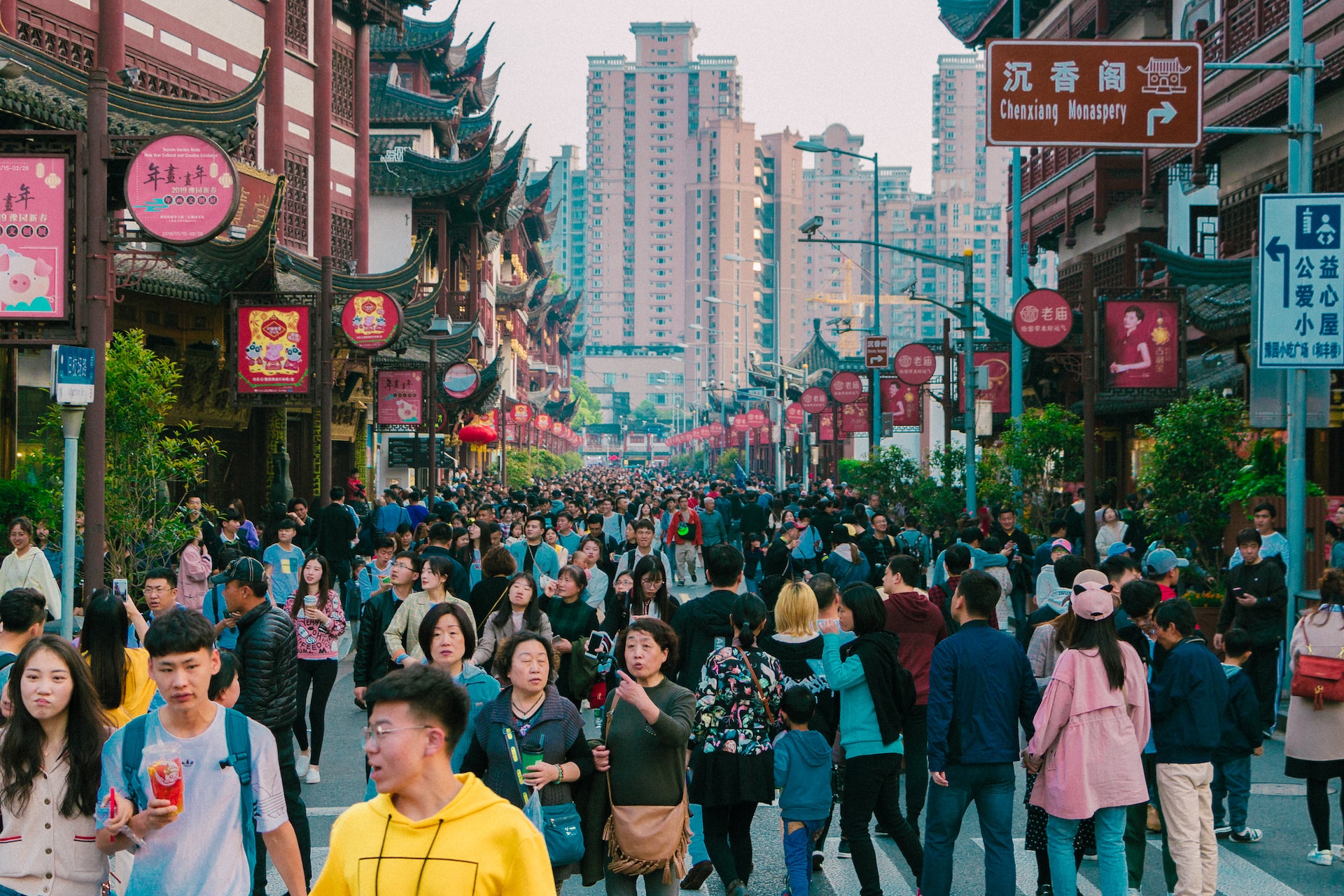 A crowd of people walking down a bustling street in an Asian city, exhibiting China's influence through its booming international trade.