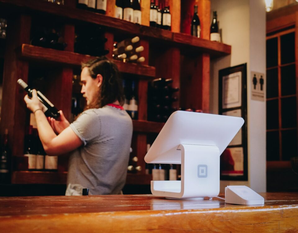 A man standing at a bar with a wine bottle in front of him, showcasing the ambiance of the e-commerce platform for wine localization.