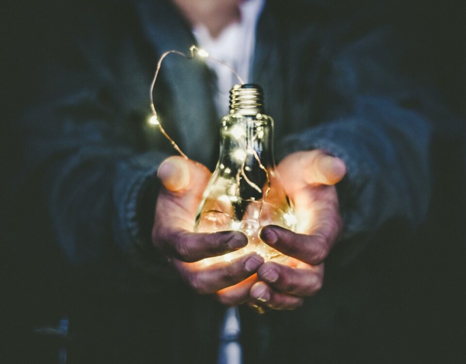 A person holding a light bulb, channeling their creativity to boost innovation in international trade.