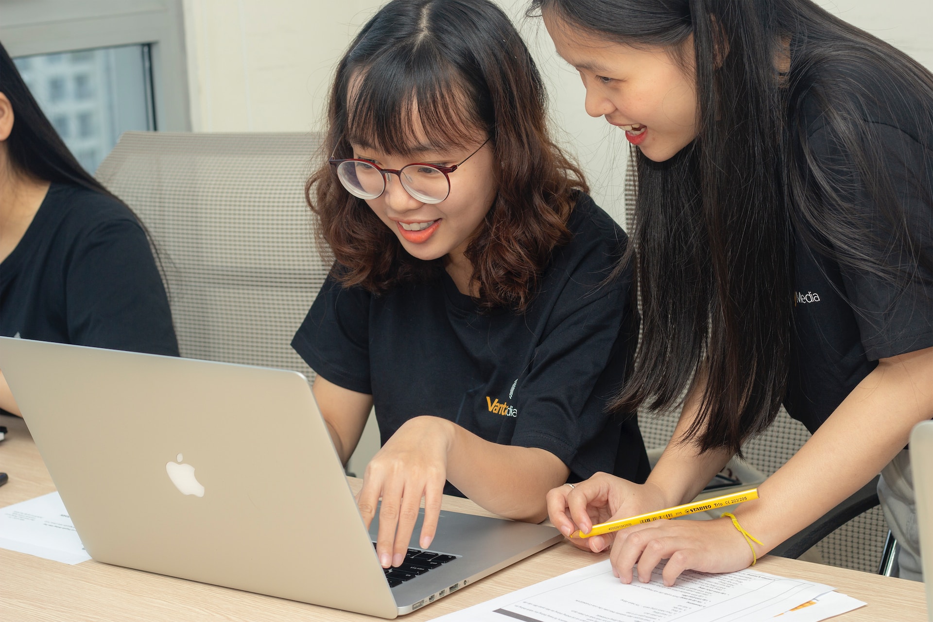 Three asian women working on a laptop while conducting competitive analysis and gathering market intelligence.