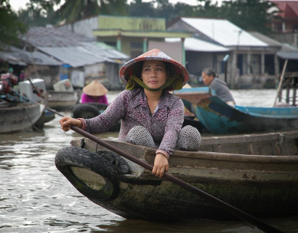 A woman demonstrating cultural intelligence while peacefully sitting in a boat on a river, engaging in cross-cultural communication.